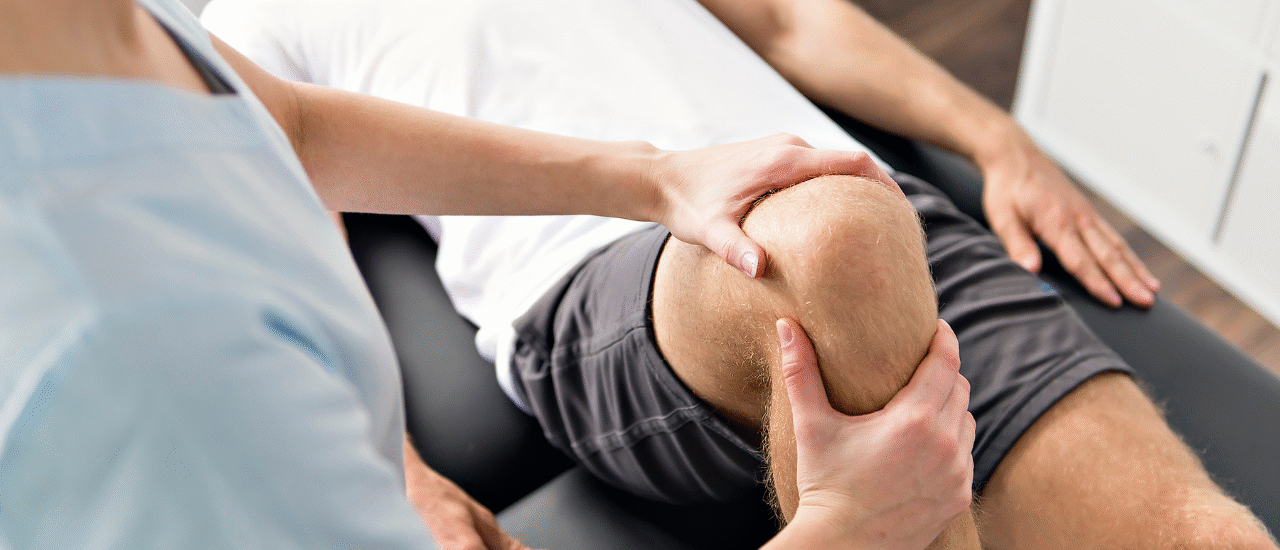 फिजिओथेरपिस्ट रुग्णाच्या पायाला व्यायाम करून वेदना कमी करण्यासाठी उपचार करत आहे