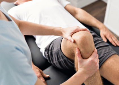 फिजिओथेरपिस्ट रुग्णाच्या पायाला व्यायाम करून वेदना कमी करण्यासाठी उपचार करत आहे