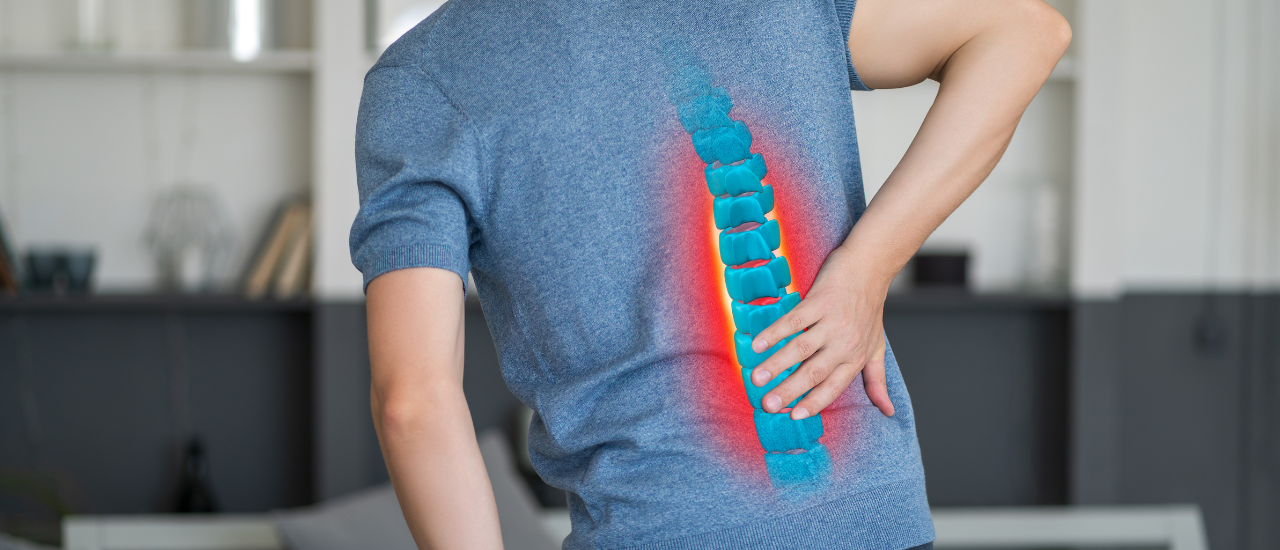 A person sitting on bed with lower back pain