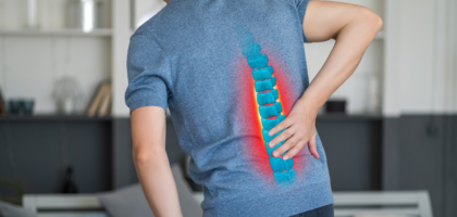 A person sitting on bed with lower back pain